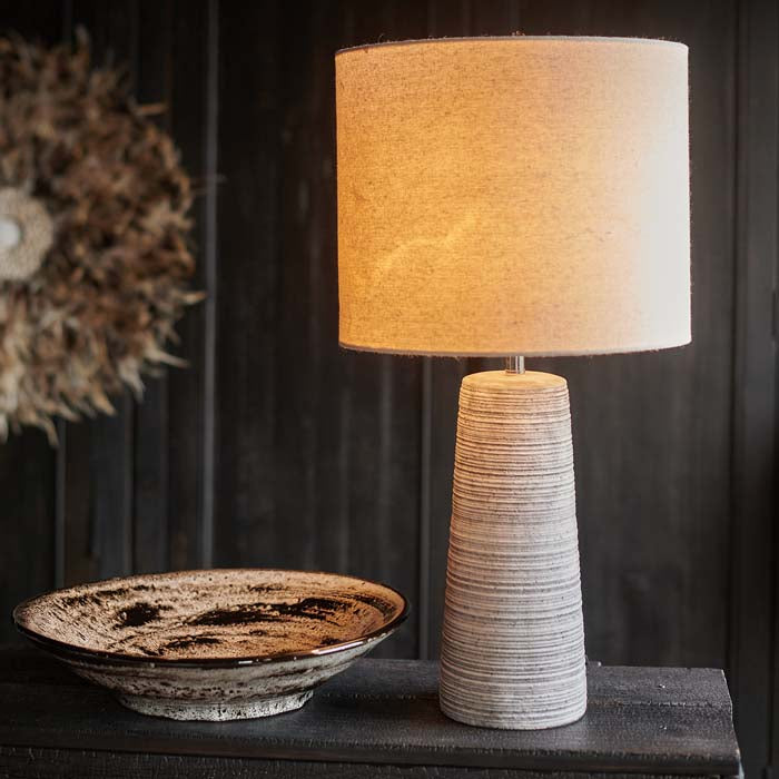 Table lamp with white-wash textured base and cream drum shade.
