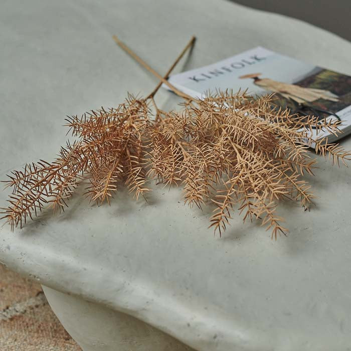 Two orange artificial foliage stems lying on a white coffee table