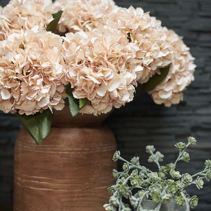 Large bunch of artificial hydrangea stems in a brown vase