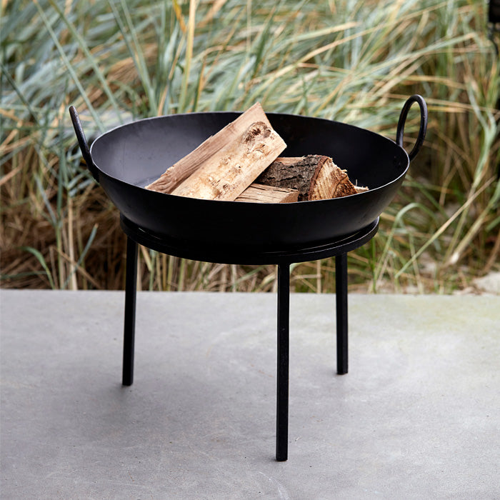 Round black metal fire pit filled with wooden logs