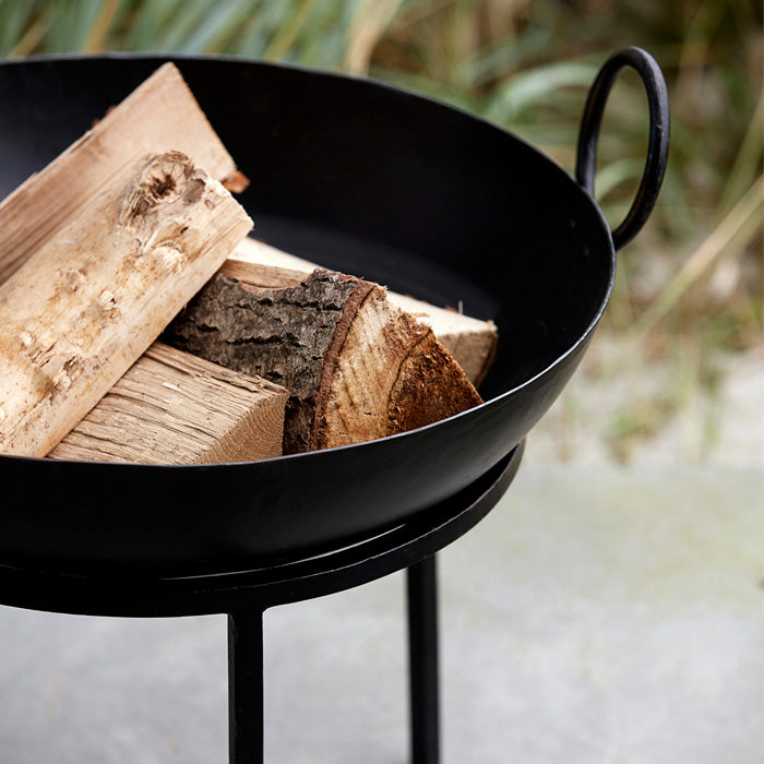 Black metal fire pit filled with wooden logs