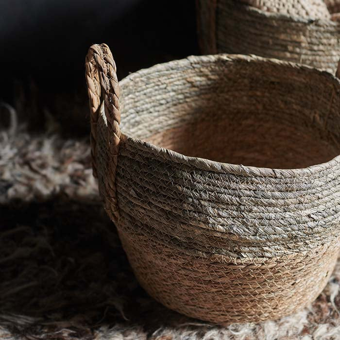 Woven two tone basket with braided handles and grey stitching