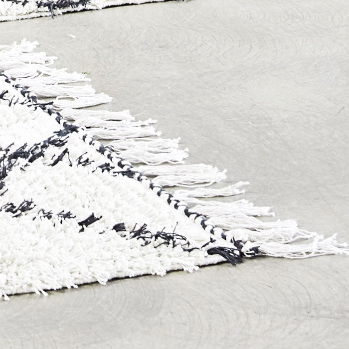 A closeup of the soft cream cotton and the fringing detail on the Berber style Keoni Rug.