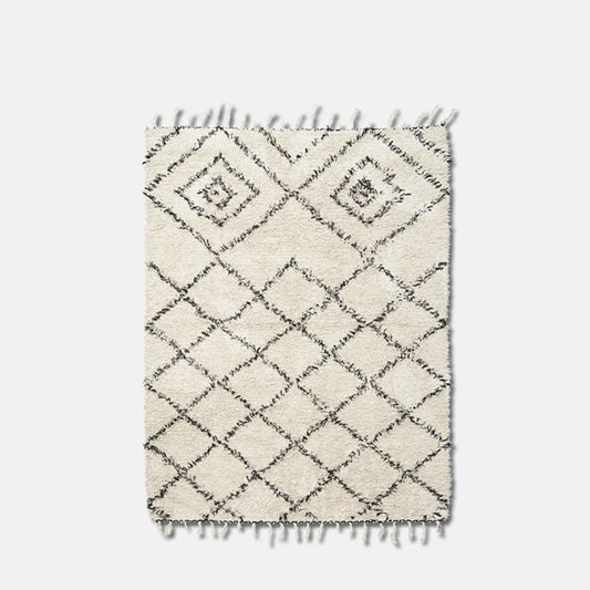 Large white and black rug with diamond pattern design and fringe details.