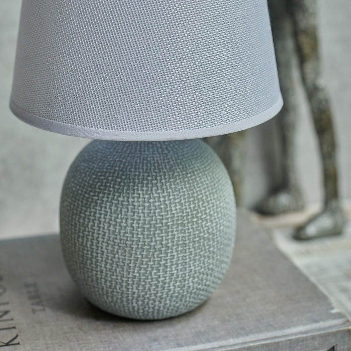 Grey table lamp with a patterned round base and plain shade