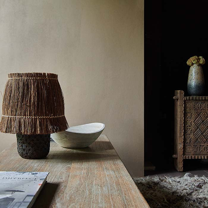 Small wooden lamp with raffia shade sat on a long wooden coffee table
