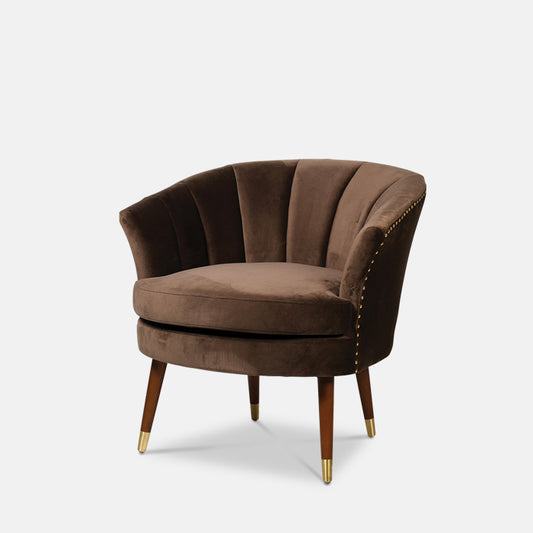Curved occasional chair upholstered in brown velvet, with four wooden legs.
