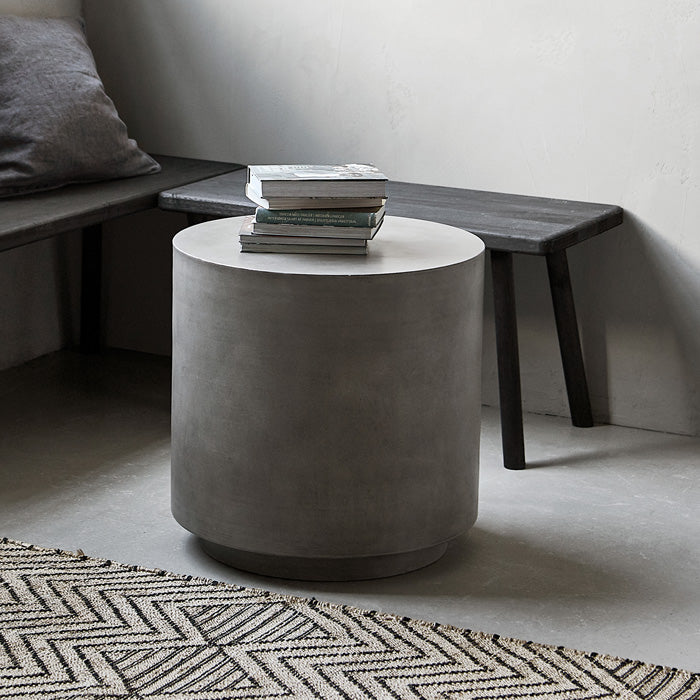Tall round side table with a stack of books on top in grey