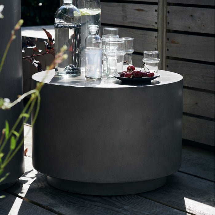 The Lander Side Table - Medium, styled with some clear drinking glasses and a bowl of cherries on a sunny patio.