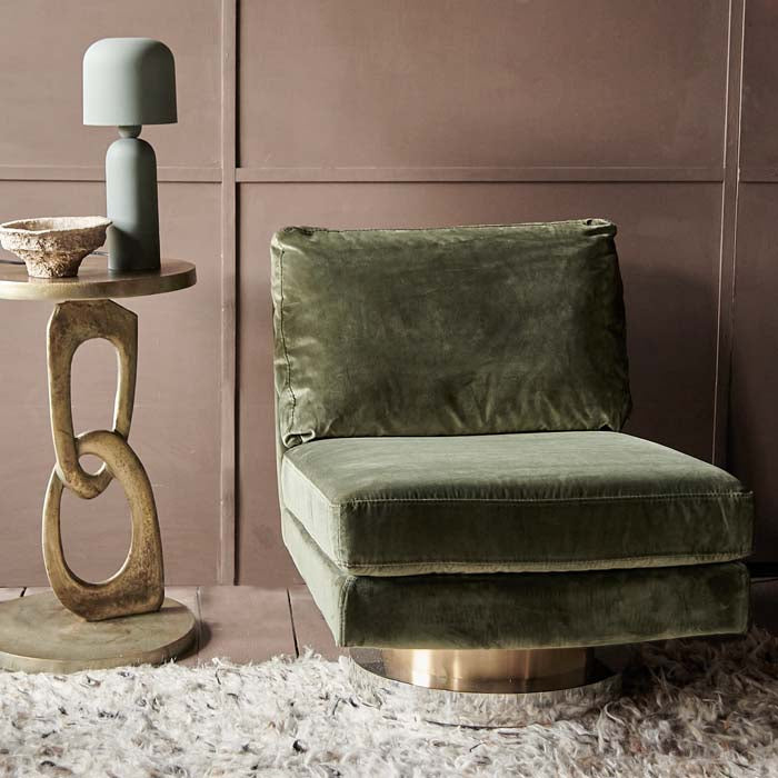 Armless occasional chair in green velvet, sitting on cylindrical gold base.