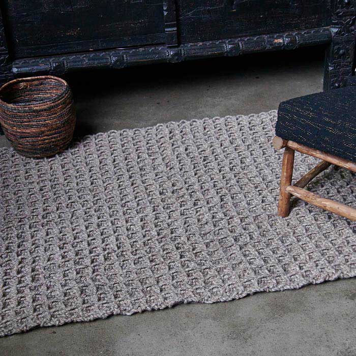 Brown rug with a raised small square pattern and a dark brown basket on top