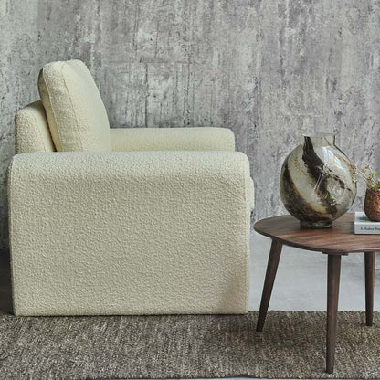 Large quirky shaped armchair with curved sides upholstered in cream boucle fabric.