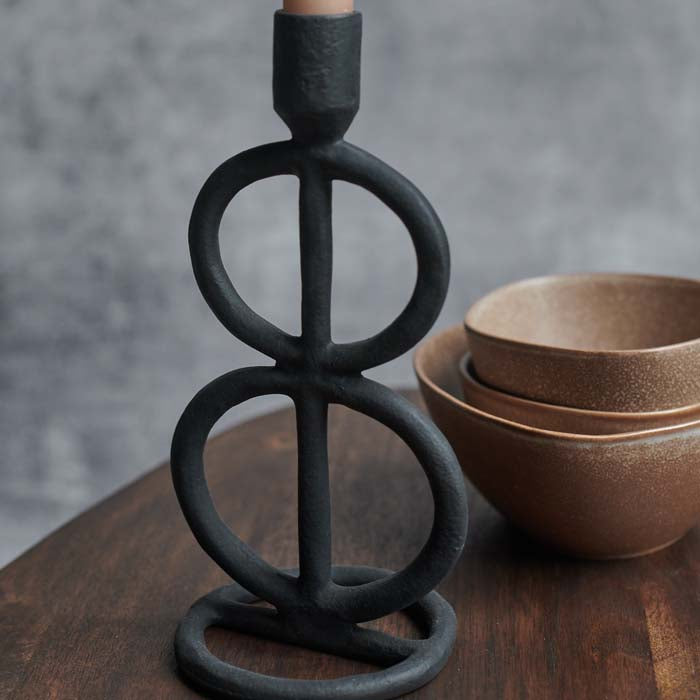 A black aluminium candleholder with curved round sculptural form.