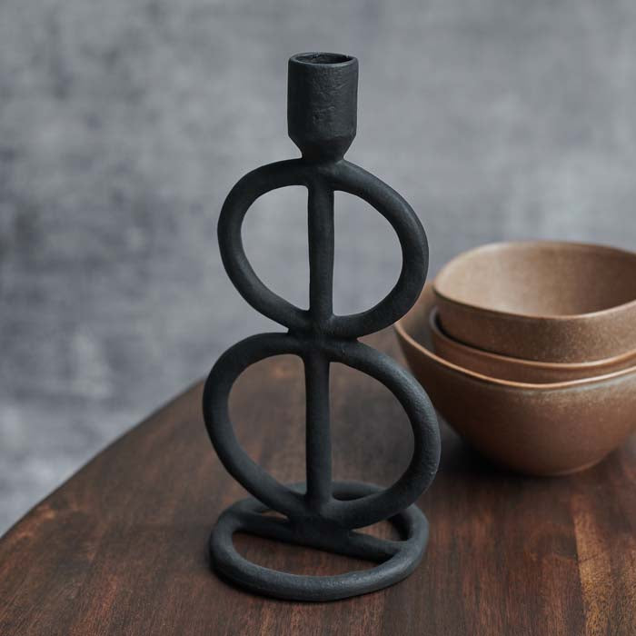 A black aluminium candlestick holder with sculptural stacked ring designs.