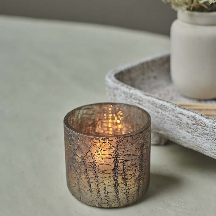 Candlelight glowing through metallic crackled glass candle holder.