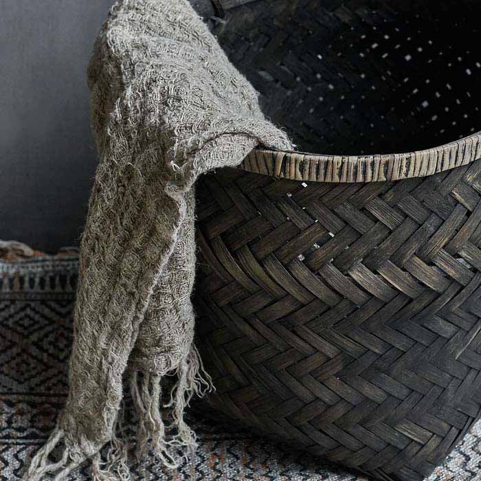 Woven basket in black with a beige towel spilling out