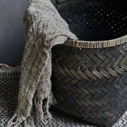 Woven basket in black with a beige towel spilling out