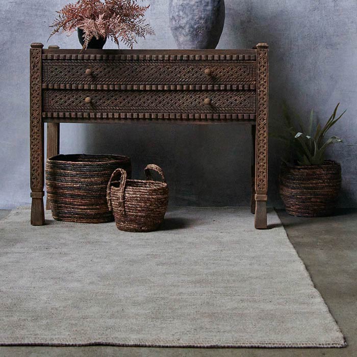 Rectangular beige rug under a wooden console with drawers and two round baskets