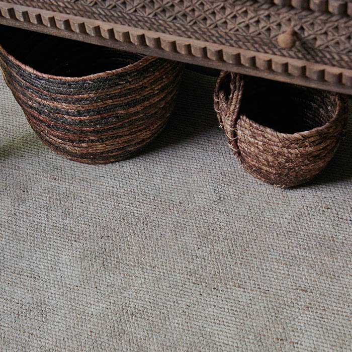 Two dark brown baskets on top of a woven beige rug 