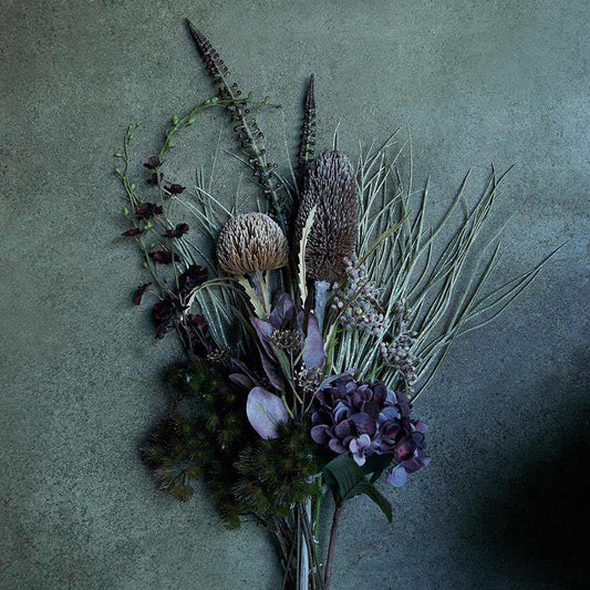 A mixed arrangement of artificial foliages and flowers in dusky purple tones.