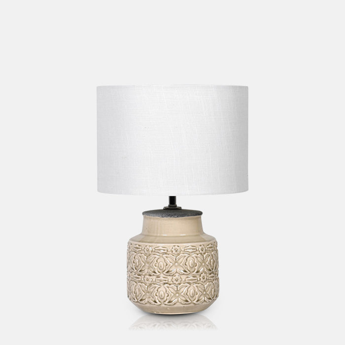 Medium table lamp with ornately decorated ceramic base in gloss beige glaze and white drum shade.