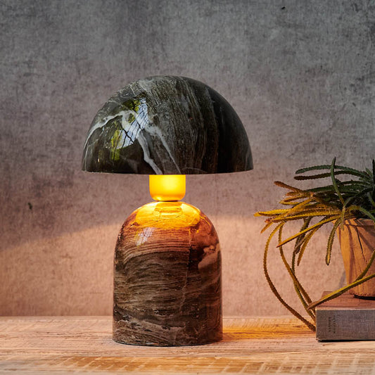 Dome shaped table lamp in a brown marble finish emitting an orange glow