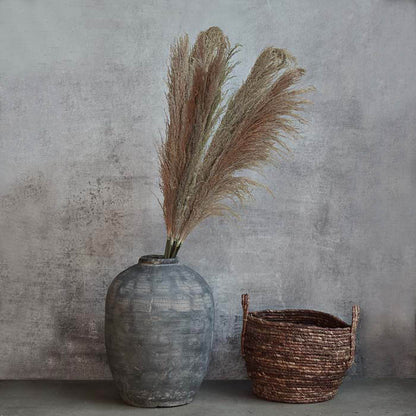 Large bunch of natural hued feathery pampas grass placed in a large grey vase