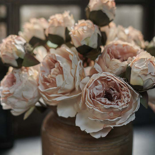 Artificial peony flowers with blush pink petals and dark green leaves.