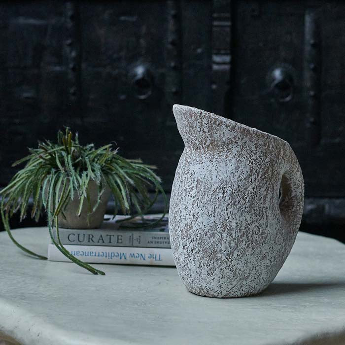 Textured white vase in a jug shape sat on a white coffee table