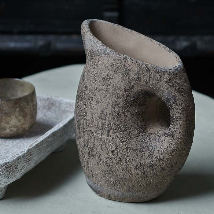 Textured dark brown vase in a jug shape sat on a white coffee table