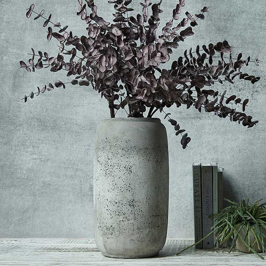 Tall distressed grey vase filled with purple eucalyptus stems