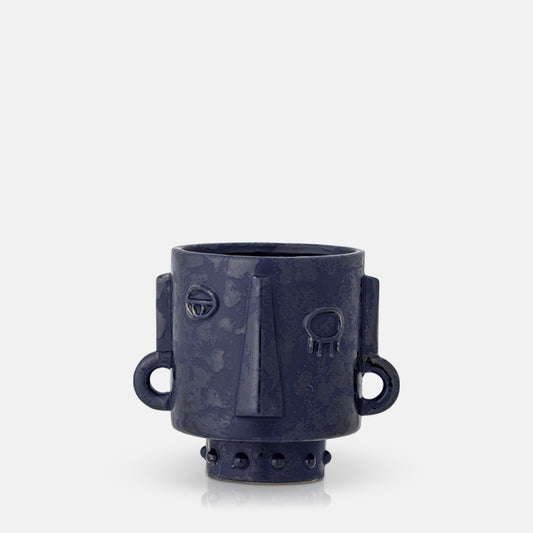 Round dark blue plant pot with a textured abstract face and raised base