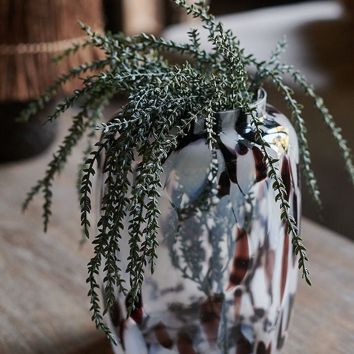 White and red marbled glass vase with two stems of faux trailing green foliage