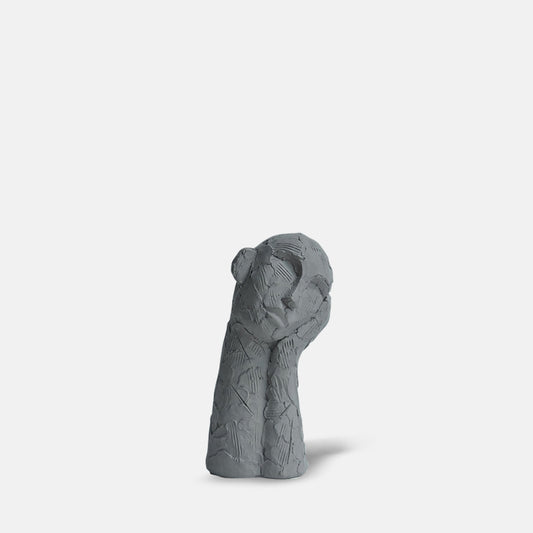 Grey face scupture with a long neck resting to the side on its hand