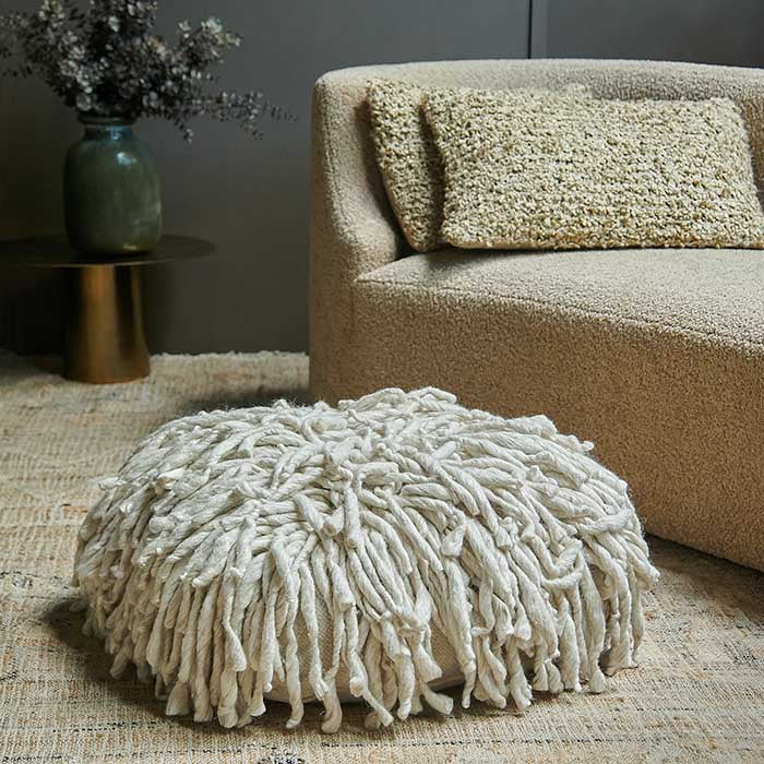 Creamy white wool pouffe with twisted shaggy texture.