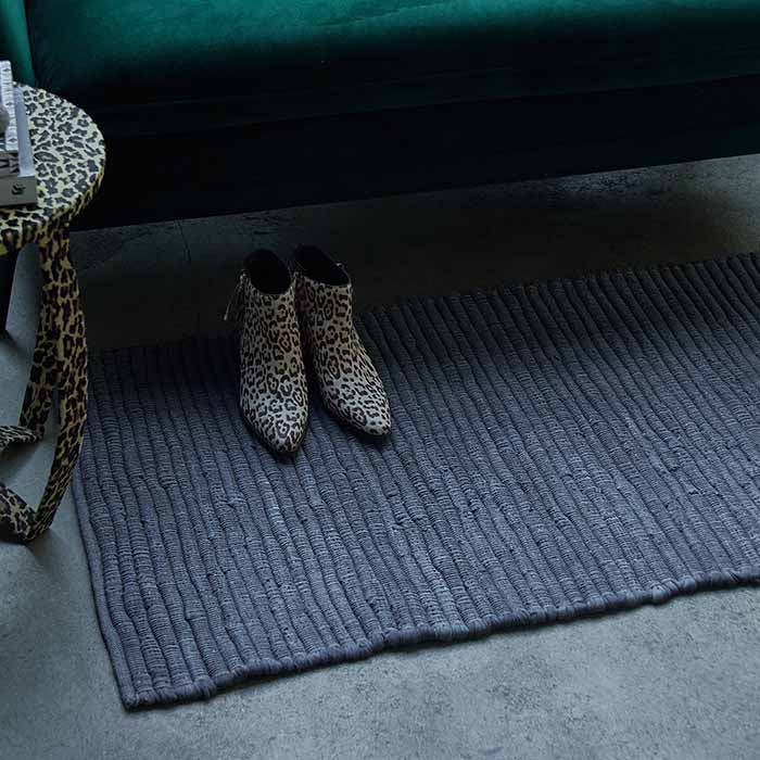 Long grey runner underneath a green sofa with a pair of leopard print boots on top