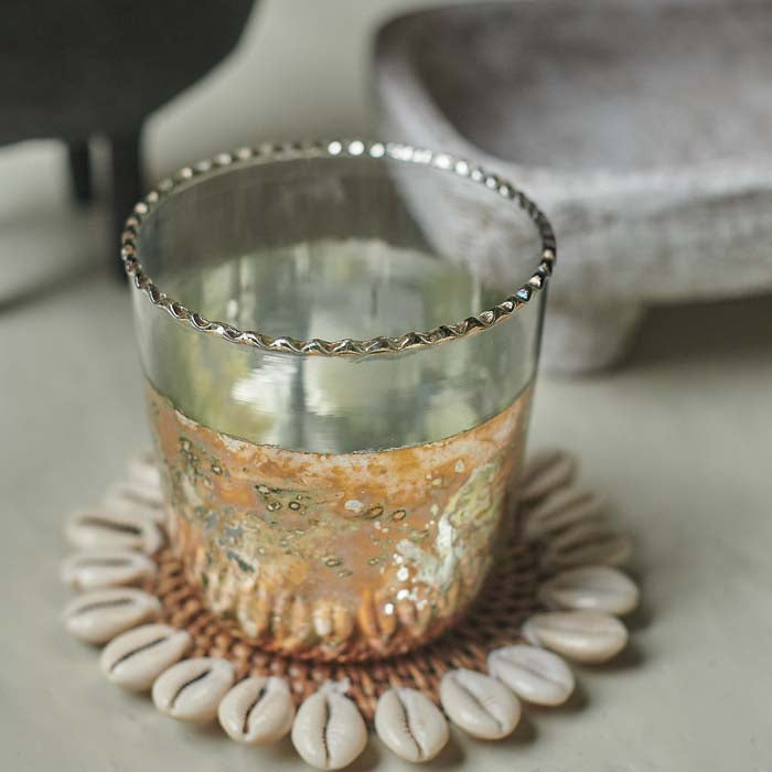 Glass candle holder with scalloped silver edge and variegated metallic body.