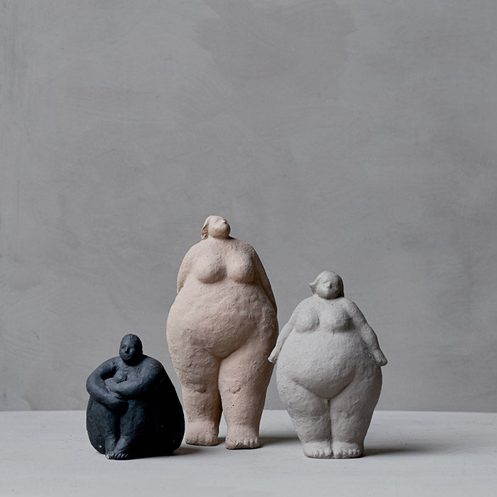Three lady sculptures in black, grey and nude tones.