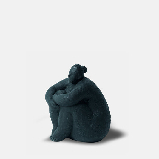 Sitting female sculpture in black with arms wrapped around its knees